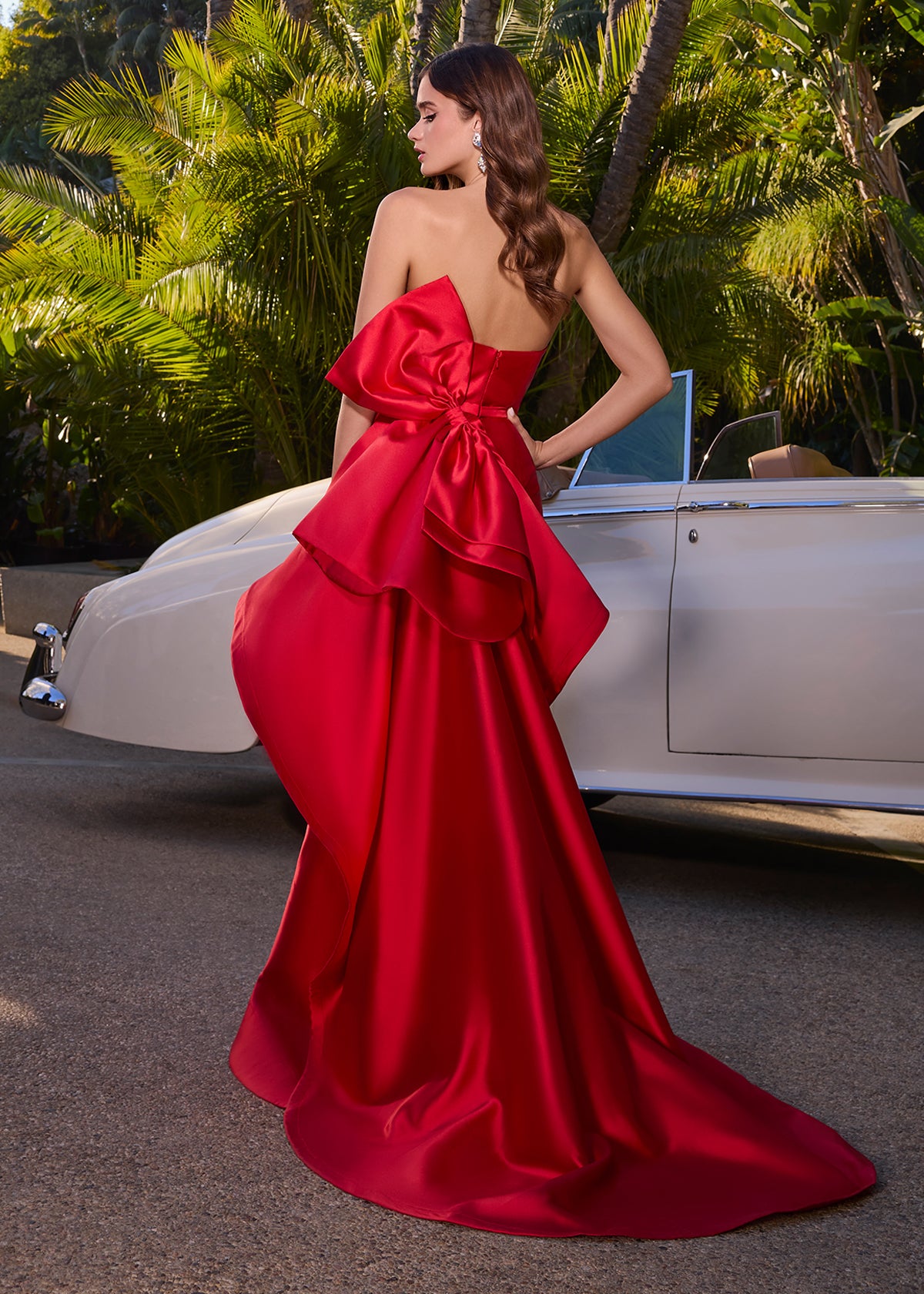 Editorial Back -  Elegant strapless mikado gown featuring a sleek belt, a left leg slit, and a statement back bow that cascades down onto the sweep train for a dramatic and sophisticated finish. Perfect for special occasions.
