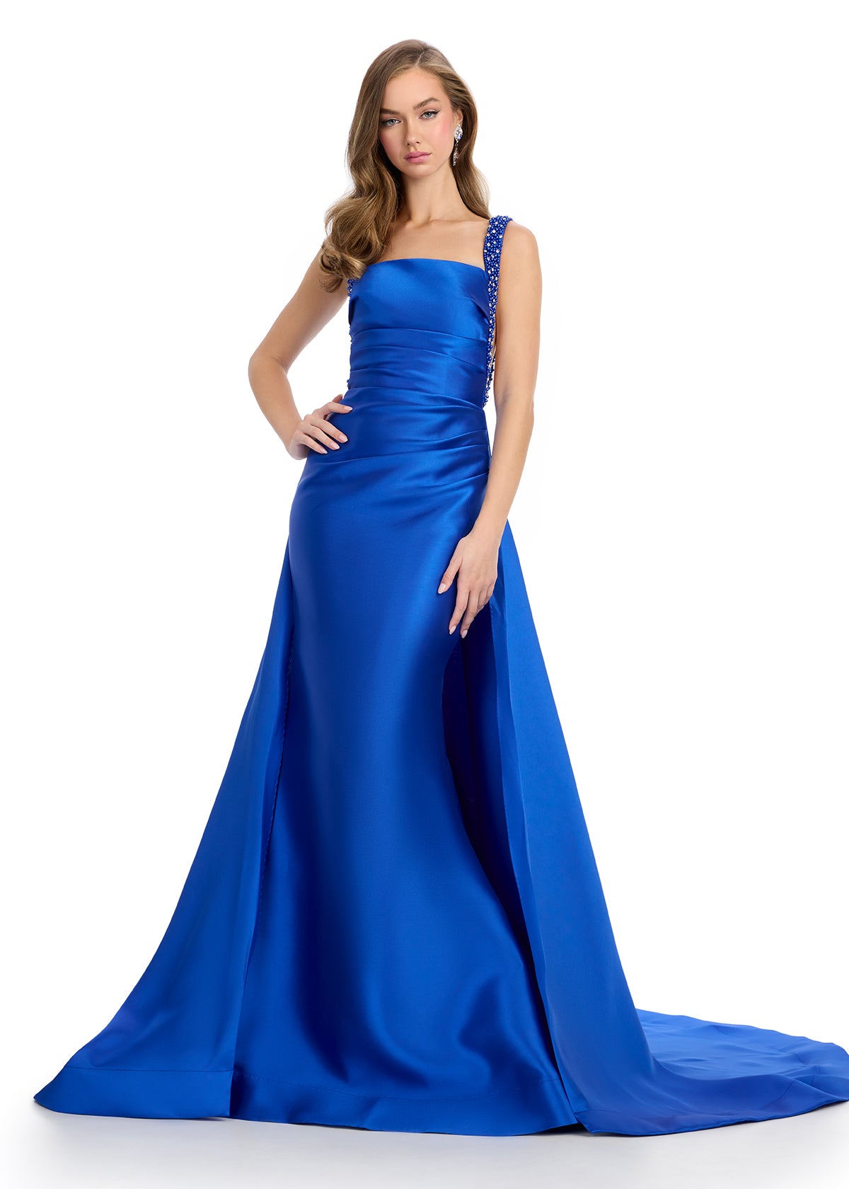 Regal mikado gown featuring fully beaded straps, a ruched bustier for a flattering fit, a sleek column skirt, and a sweeping overskirt for a dramatic, timeless look. Perfect for making a grand entrance.