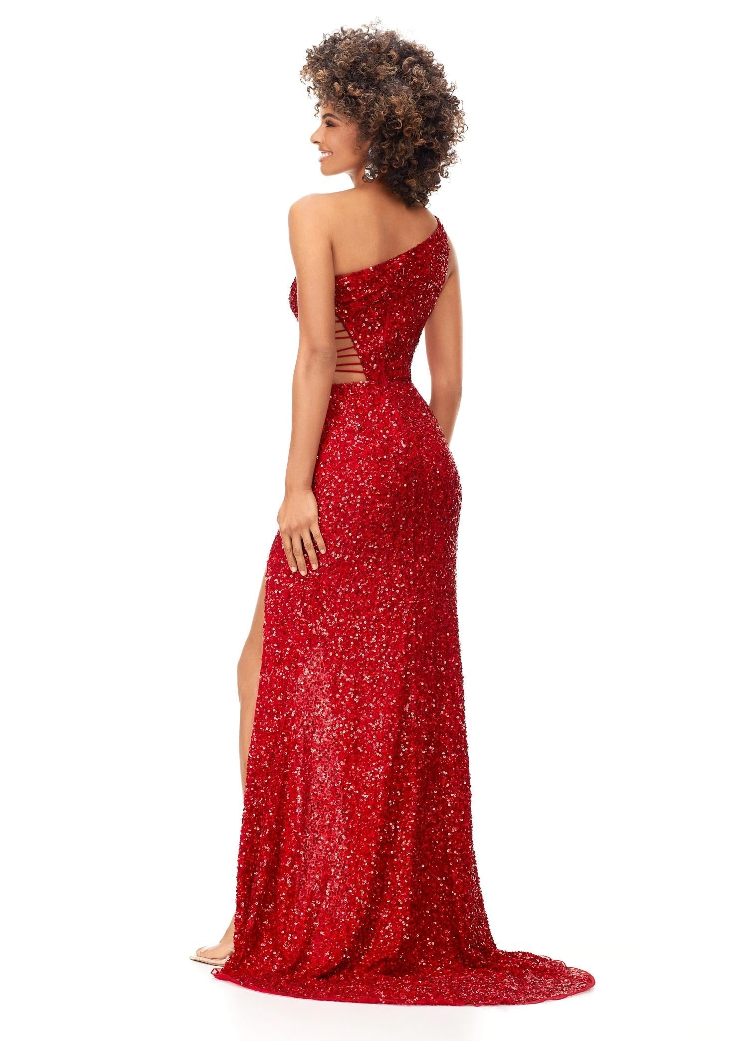 Back view. Red ASHLEYlauren 11288 stunning one shoulder fully hand-beaded gown featuring modern cut outs, criss cross waist straps, a left leg slit, and a sweep train for a bold and statement-making entrance.