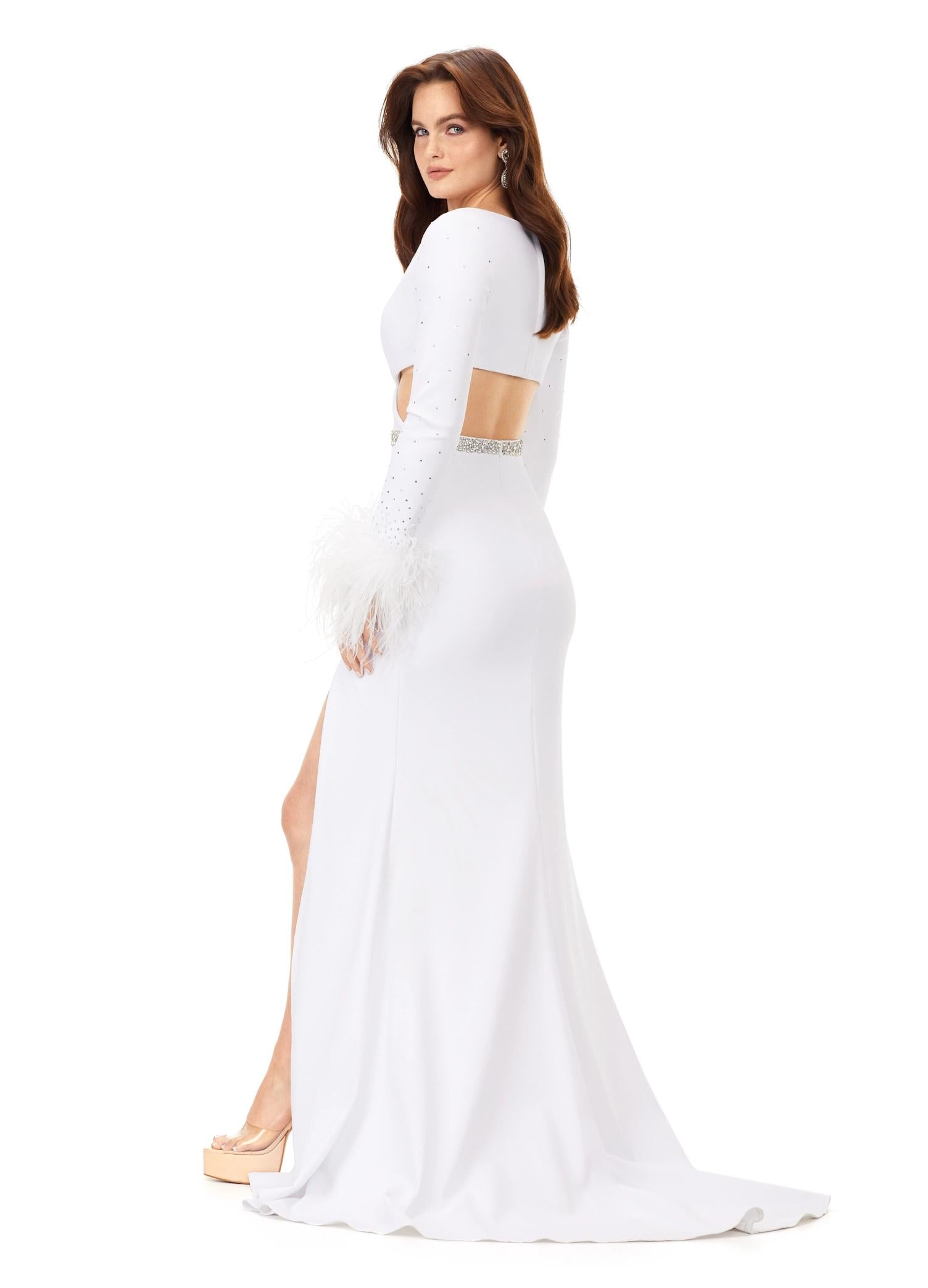 Back view. White ASHLEYlauren 11308 striking scuba gown featuring a deep V-neckline, criss-cross cut out bodice, crystal waistline, long sleeves adorned with heat-set stones and feather trim, a fitted skirt, and a left leg slit for a bold and glamorous statement look.