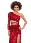 Front. Red ASHLEYlauren 11261 fully hand-beaded one shoulder gown featuring a shark bite cut out at the waist, left leg slit, and intricately placed bead pattern to accentuate curves, complete with scattered fringe along the shoulder and waistline for a bold and glamorous look.