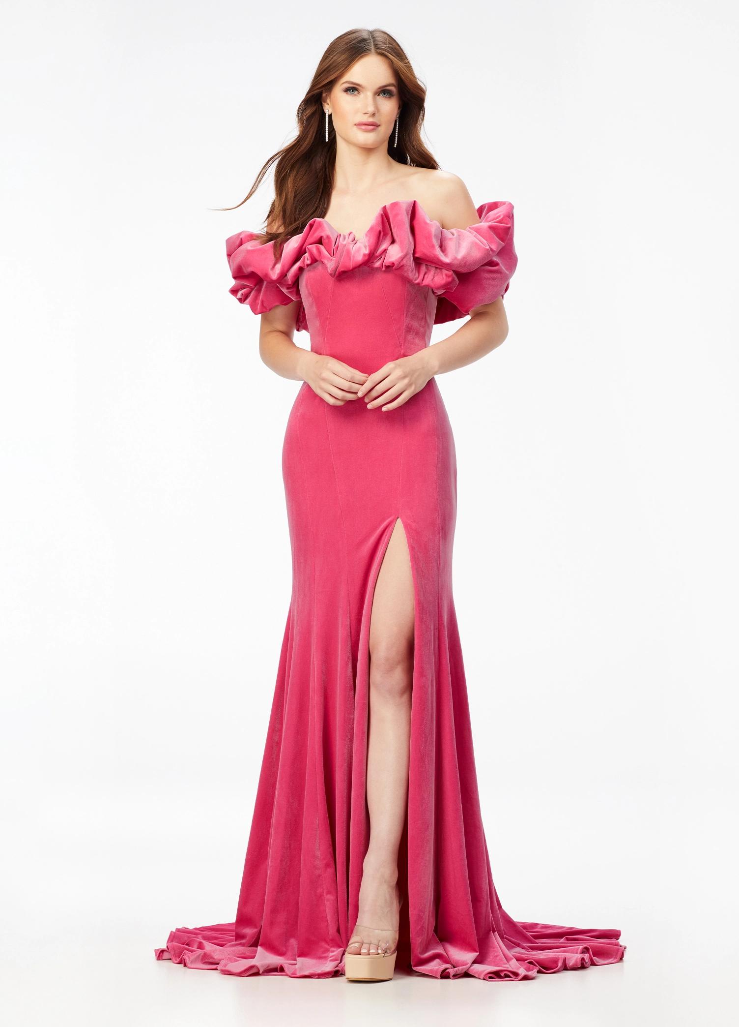 Pink ASHLEYlauren 11217 – A magnificent off-shoulder velvet gown featuring oversized ruffle details, a contour seamed skirt with a left leg slit, and a dramatic train. Perfect for making a bold, elegant statement at any event.