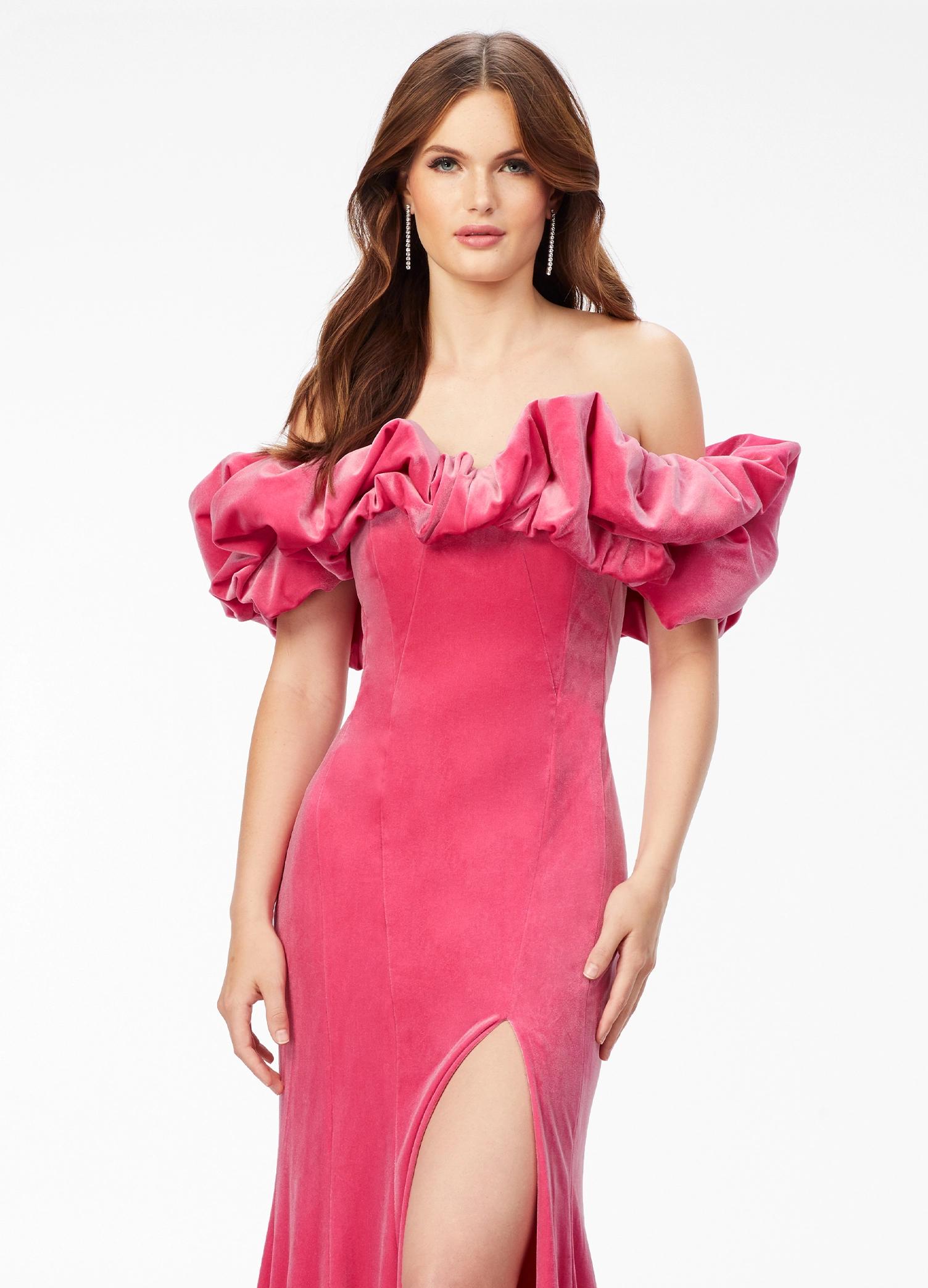 Pink ASHLEYlauren 11217 – A magnificent off-shoulder velvet gown featuring oversized ruffle details, a contour seamed skirt with a left leg slit, and a dramatic train. Perfect for making a bold, elegant statement at any event.