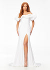 White ASHLEYlauren 11217 – A magnificent off-shoulder velvet gown featuring oversized ruffle details, a contour seamed skirt with a left leg slit, and a dramatic train. Perfect for making a bold, elegant statement at any event.