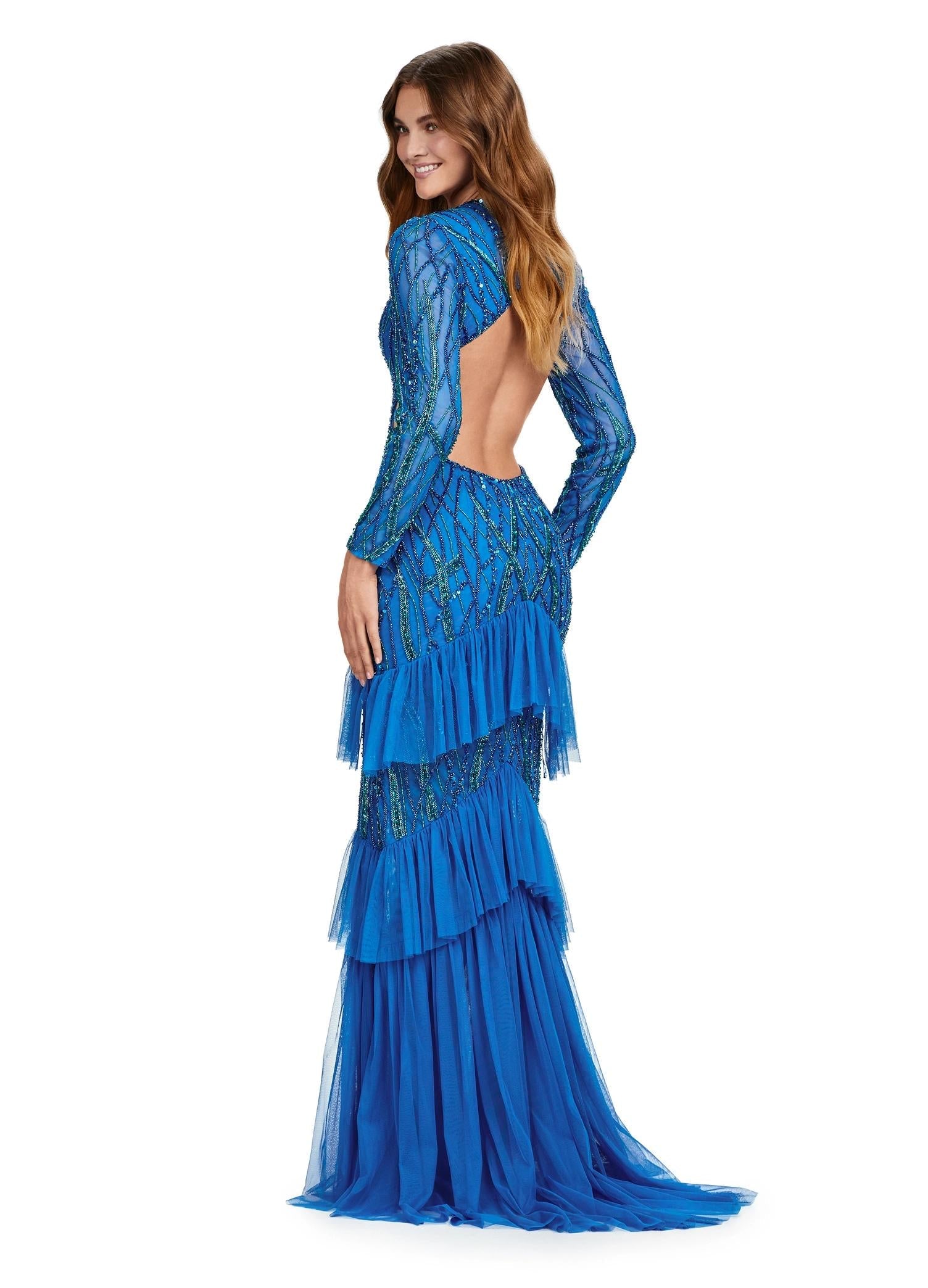 Back view. Peacock ASHLEYlauren 11436 stunning fully beaded gown featuring a V-neckline, open back, long sleeves, and a tiered ruffle skirt with a center slit for a show-stopping entrance.