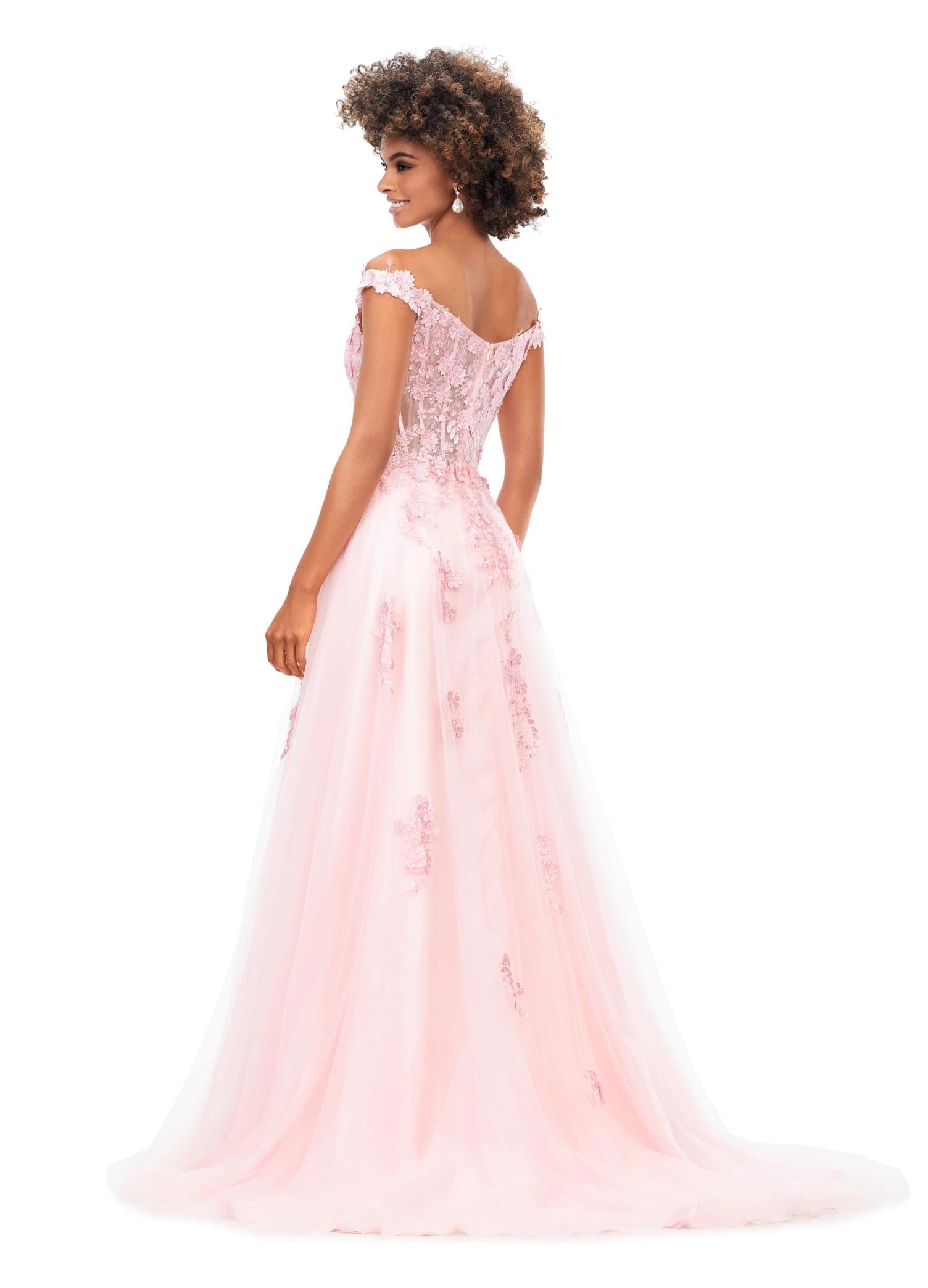 Back view. Pink ASHLEYlauren 11376 fairytale-inspired off-shoulder gown featuring an illusion corset bodice, delicate 3D lace flower appliques cascading throughout layers of tulle, and a left leg slit for an ethereal and romantic look.