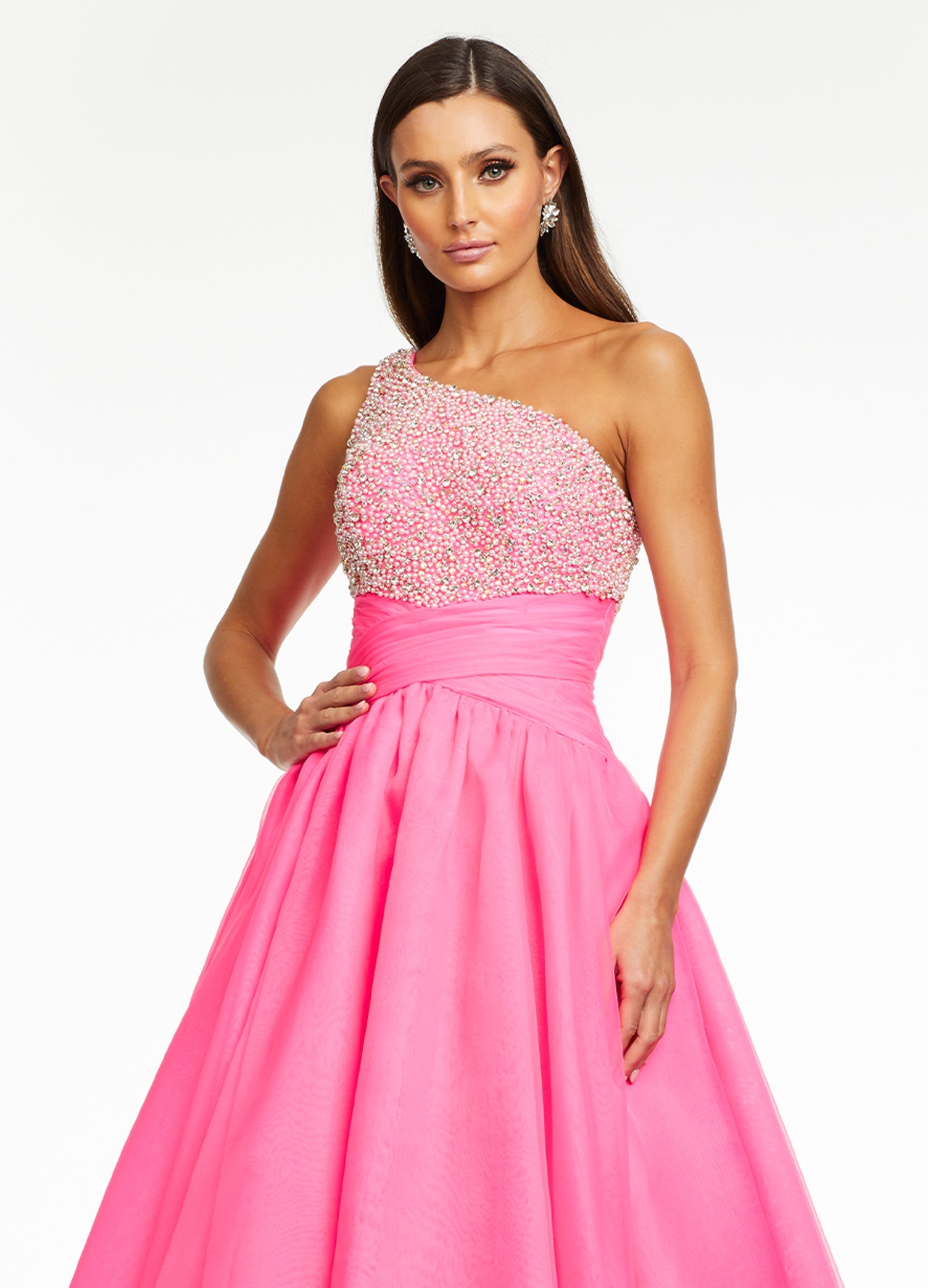 Pink ASHLEYlauren 11127 – An elegant one-shoulder organza ball gown featuring an encrusted crystal and pearl detail bustier, a ruched wrap waist for a flattering silhouette, and a full ball gown skirt. Perfect for any formal event.